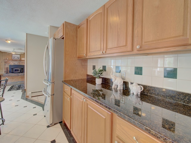 kitchen with freestanding refrigerator, light brown cabinets, light tile patterned floors, and a baseboard radiator