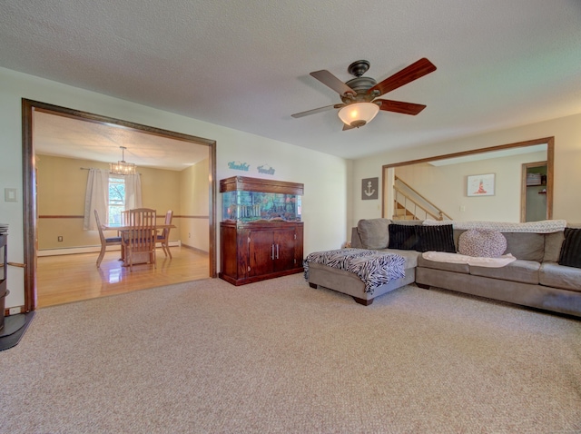 carpeted living room featuring stairway, a baseboard radiator, and ceiling fan with notable chandelier