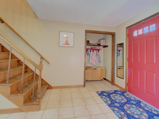 foyer featuring baseboards, light tile patterned flooring, and stairway