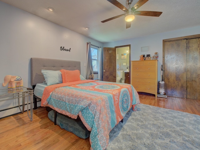 bedroom featuring a closet, a ceiling fan, ensuite bath, and wood finished floors