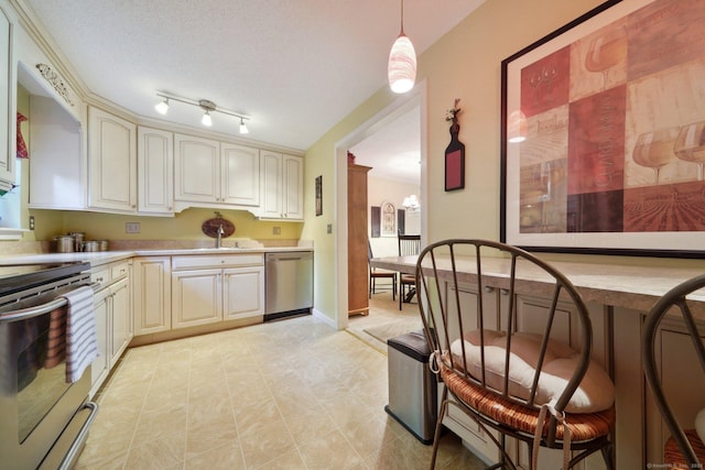 kitchen with light countertops, cream cabinetry, a sink, hanging light fixtures, and stainless steel appliances