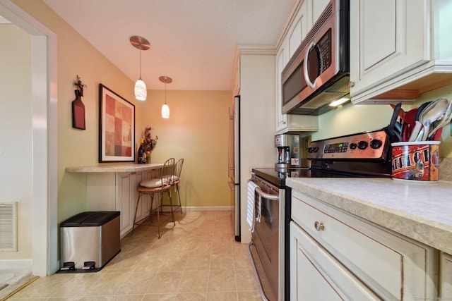 kitchen with white cabinets, decorative light fixtures, appliances with stainless steel finishes, and light countertops