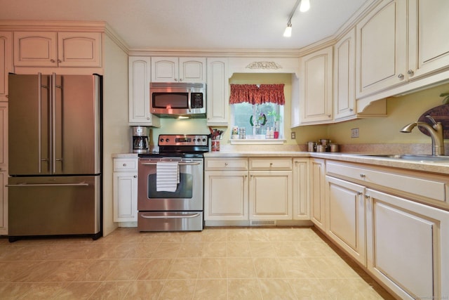 kitchen with a sink, light countertops, stainless steel appliances, cream cabinetry, and visible vents