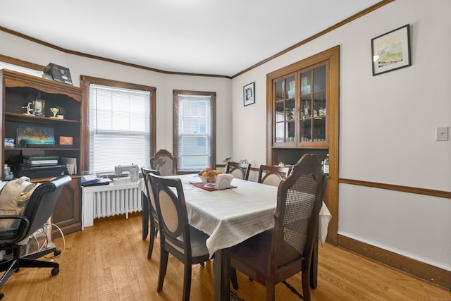 dining space featuring light wood finished floors, ornamental molding, radiator, and baseboards