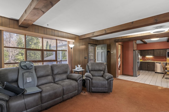 living room featuring wooden walls, light tile patterned floors, light carpet, and beam ceiling