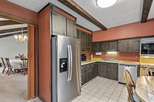 kitchen featuring appliances with stainless steel finishes, a sink, light countertops, beamed ceiling, and an inviting chandelier