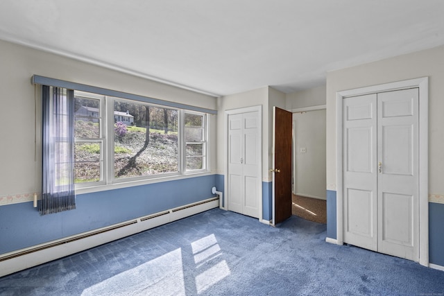 unfurnished bedroom with a baseboard radiator, carpet, and two closets