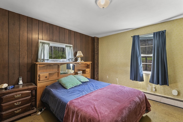 bedroom with carpet flooring, a baseboard heating unit, and multiple windows