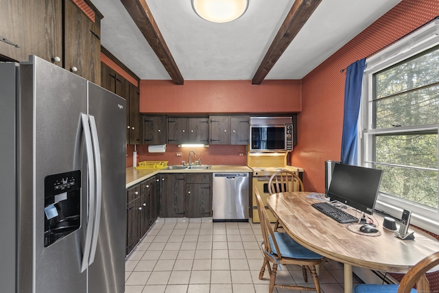 kitchen featuring a healthy amount of sunlight, a sink, light countertops, stainless steel appliances, and light tile patterned flooring