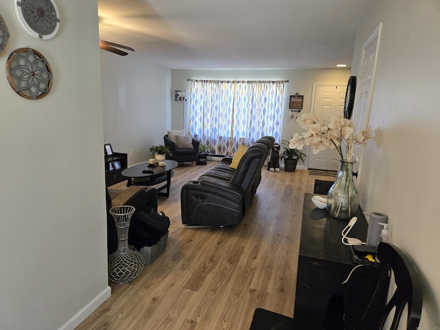 living area featuring a ceiling fan, baseboards, and wood finished floors
