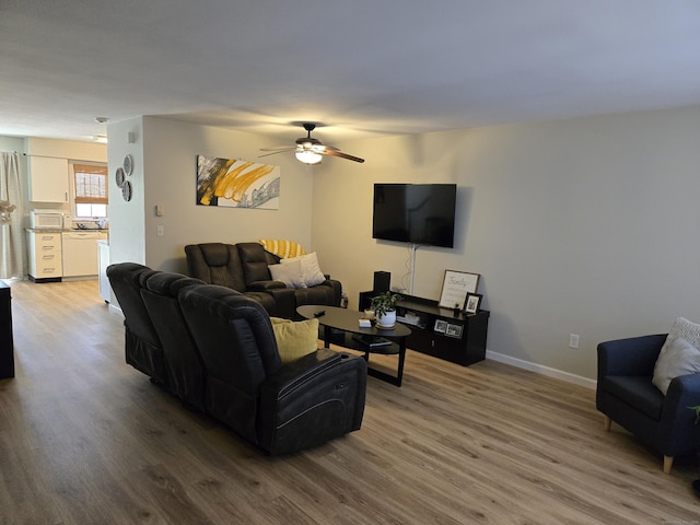 living area featuring a toaster, baseboards, ceiling fan, and wood finished floors
