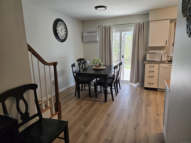 dining space featuring a wall mounted air conditioner, light wood-style flooring, and stairway