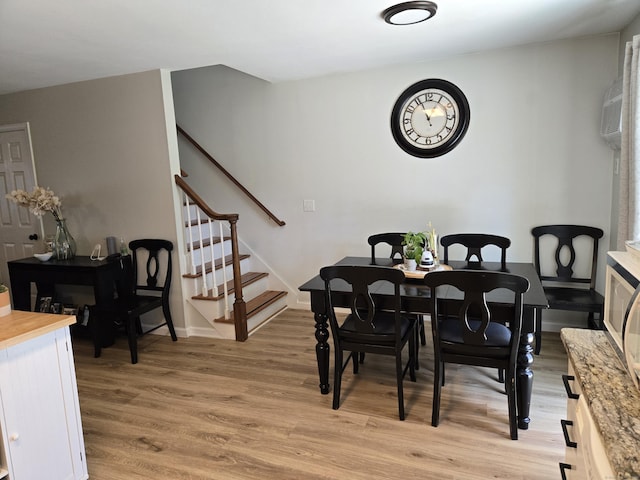 dining area with light wood-style floors and stairs