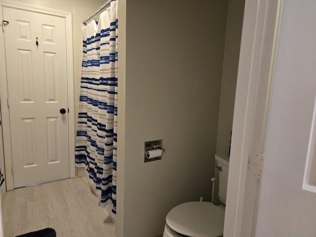 bathroom featuring toilet, curtained shower, and wood finished floors