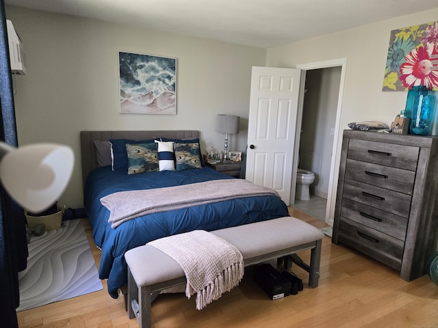 bedroom with light wood-style floors and connected bathroom