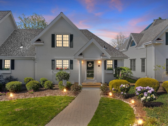 traditional home with roof with shingles and a front yard