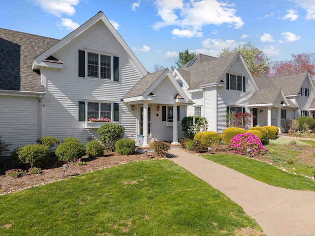 traditional-style house with a shingled roof and a front yard
