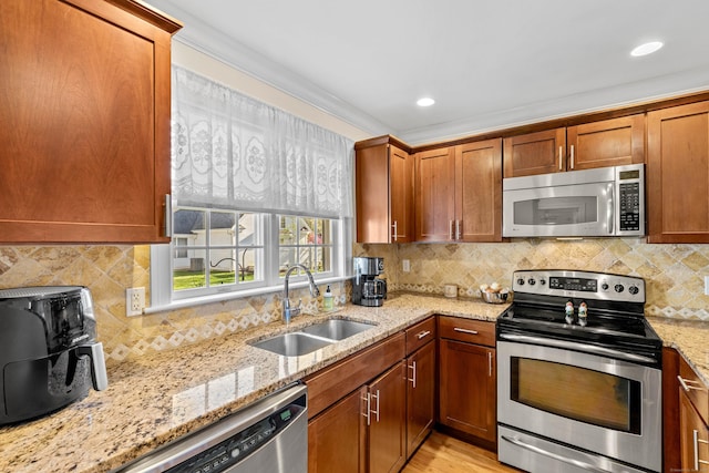 kitchen featuring a sink, appliances with stainless steel finishes, backsplash, and light stone countertops