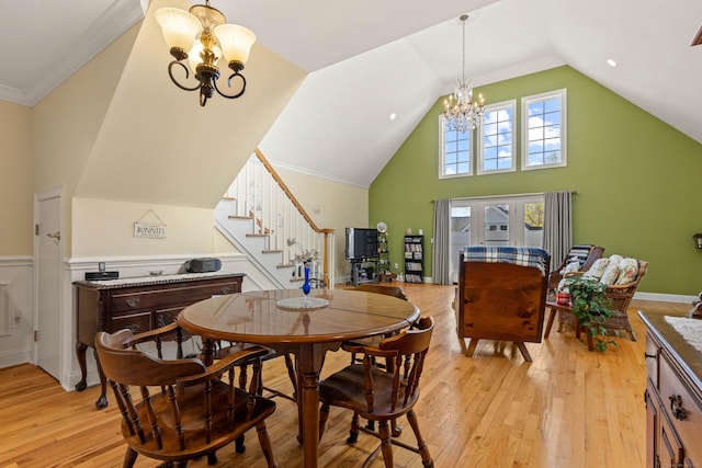 dining space with vaulted ceiling, an inviting chandelier, light wood-style flooring, and stairway