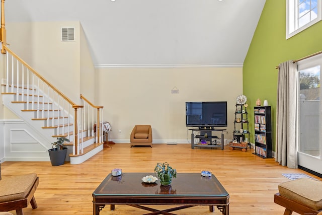 living room featuring crown molding, stairs, wood finished floors, and high vaulted ceiling