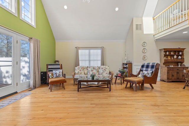 living room with high vaulted ceiling, light wood-type flooring, and visible vents