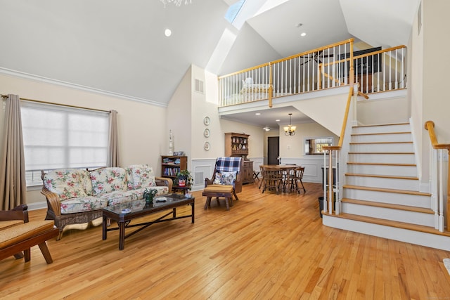 living area with high vaulted ceiling, a wainscoted wall, stairs, visible vents, and hardwood / wood-style flooring