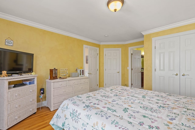 bedroom featuring crown molding, baseboards, wood finished floors, and a closet