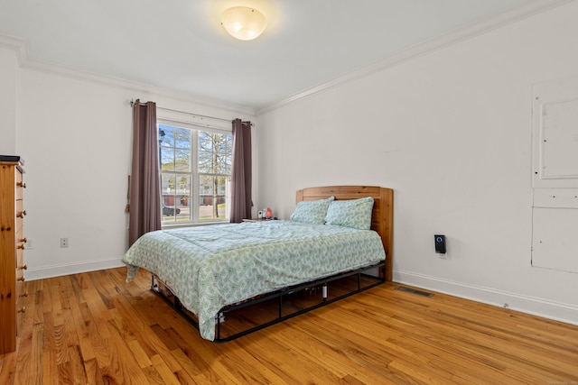 bedroom featuring baseboards, visible vents, ornamental molding, and light wood-style flooring