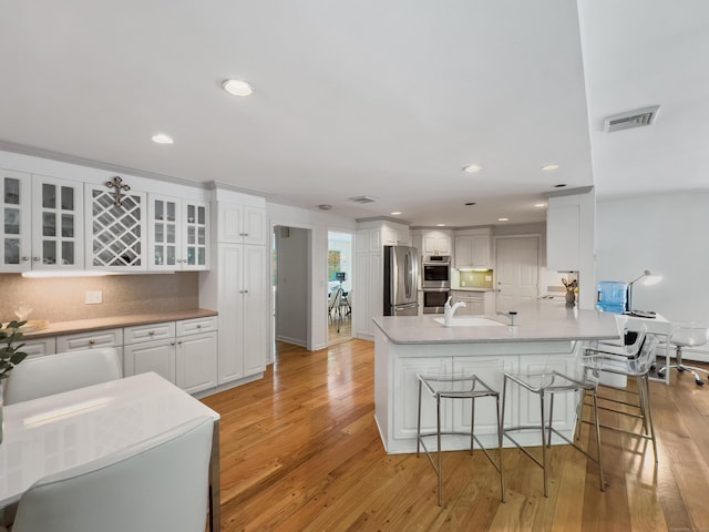 34 Longmeadows Rd, Wilton, CT 06897 - kitchen with visible vents, a breakfast bar, white cabinets, a sink, and stainless steel appliances
