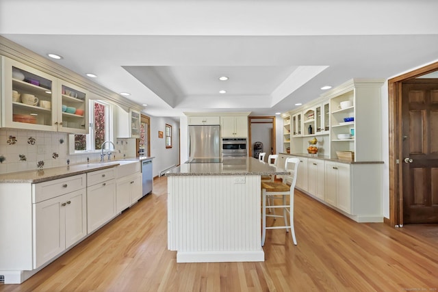 4 Walnut Ridge Rd, New Fairfield, CT 06812 - kitchen featuring backsplash, appliances with stainless steel finishes, a center island, light wood finished floors, and a tray ceiling