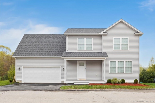 traditional home with a porch, a garage, and aphalt driveway