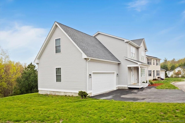 view of side of home with a shingled roof, a yard, a garage, and aphalt driveway