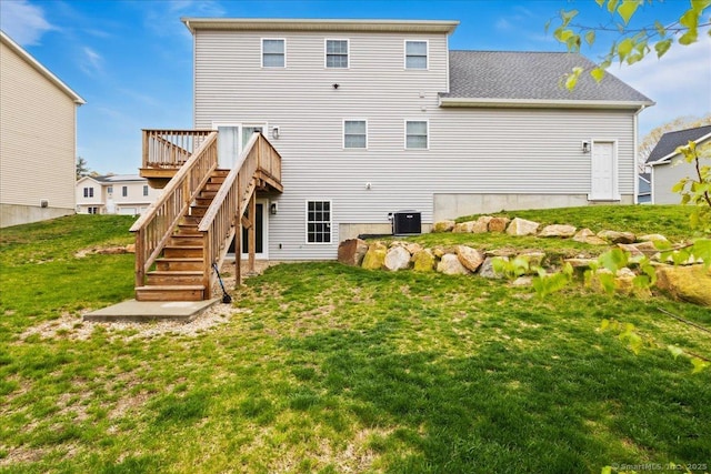 rear view of property with a yard, central air condition unit, a deck, stairway, and roof with shingles