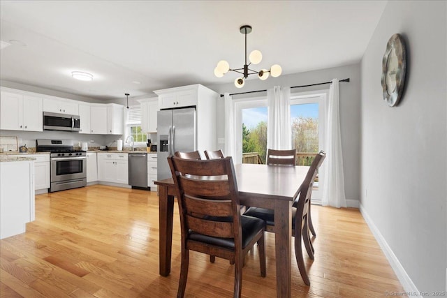 dining area featuring an inviting chandelier, baseboards, and light wood finished floors