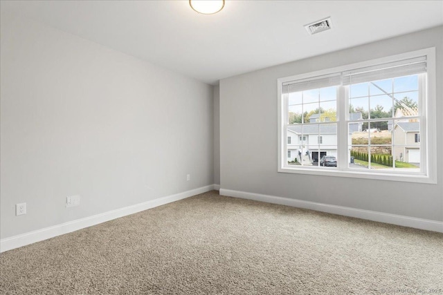 empty room featuring carpet, baseboards, and visible vents