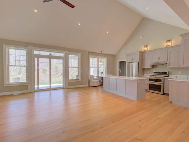kitchen with ceiling fan, light countertops, high vaulted ceiling, open floor plan, and stainless steel appliances