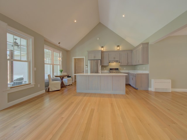 kitchen with light wood finished floors, light countertops, high vaulted ceiling, stainless steel appliances, and under cabinet range hood