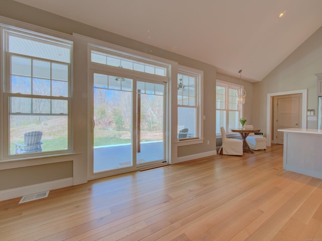 doorway to outside featuring visible vents, light wood-style flooring, baseboards, and a chandelier