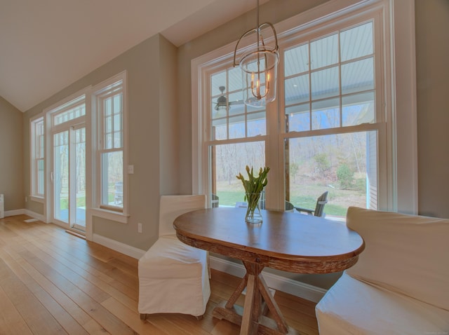 dining room with baseboards, light wood finished floors, and a notable chandelier