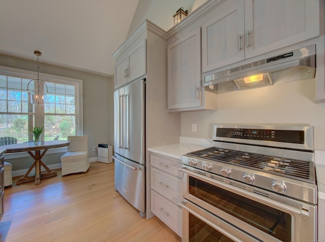 kitchen featuring light stone countertops, appliances with stainless steel finishes, light wood-style flooring, decorative light fixtures, and under cabinet range hood