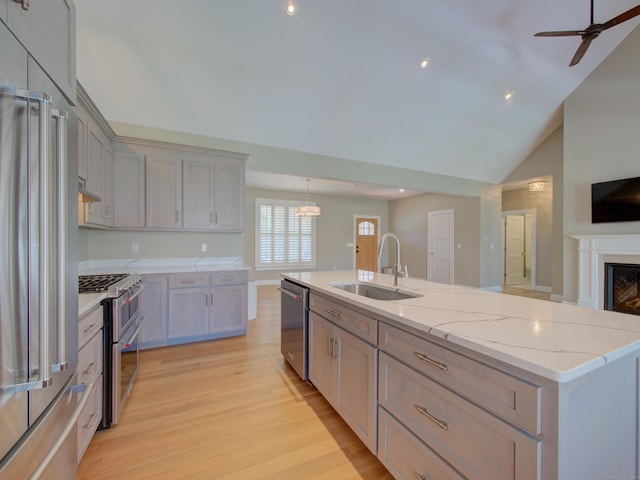 kitchen featuring open floor plan, ceiling fan, a sink, light wood finished floors, and premium appliances