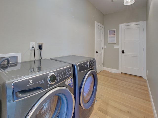 clothes washing area featuring baseboards, separate washer and dryer, laundry area, and light wood-style flooring
