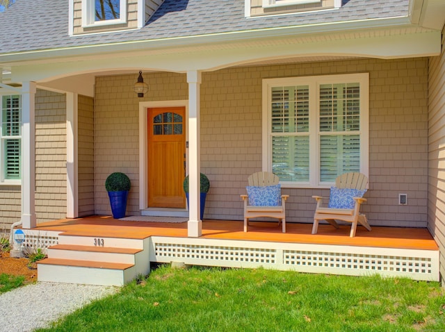 doorway to property featuring roof with shingles and covered porch