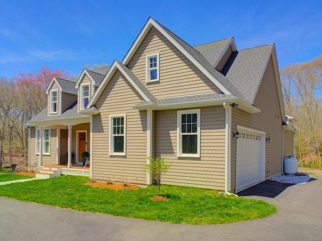 view of front of property featuring a front lawn, aphalt driveway, covered porch, roof with shingles, and an attached garage