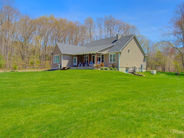 back of house featuring a porch, a yard, and a chimney