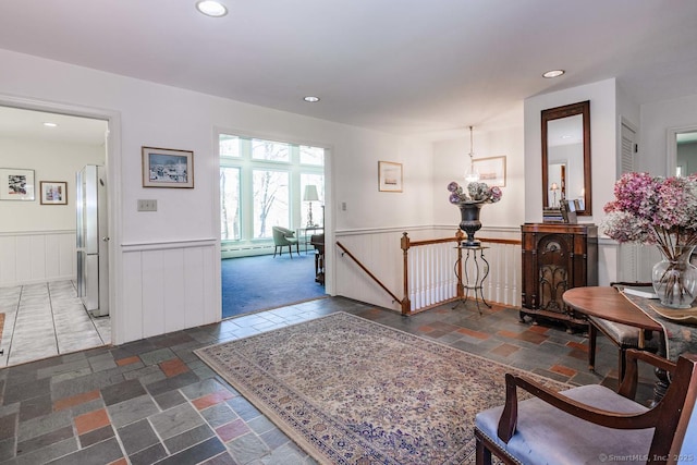 interior space featuring a baseboard radiator, wainscoting, recessed lighting, and stone tile floors