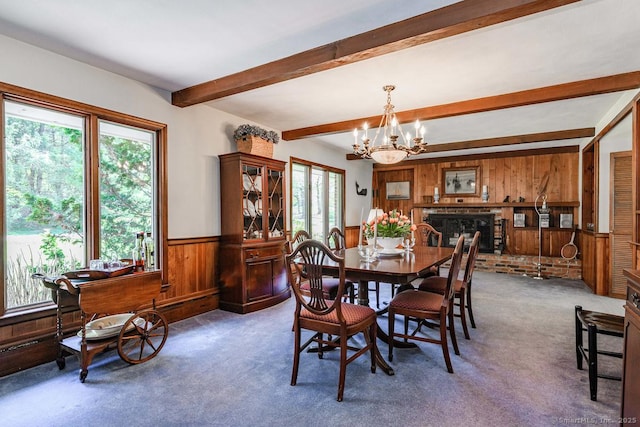 carpeted dining area with an inviting chandelier, wainscoting, a fireplace, beamed ceiling, and wooden walls