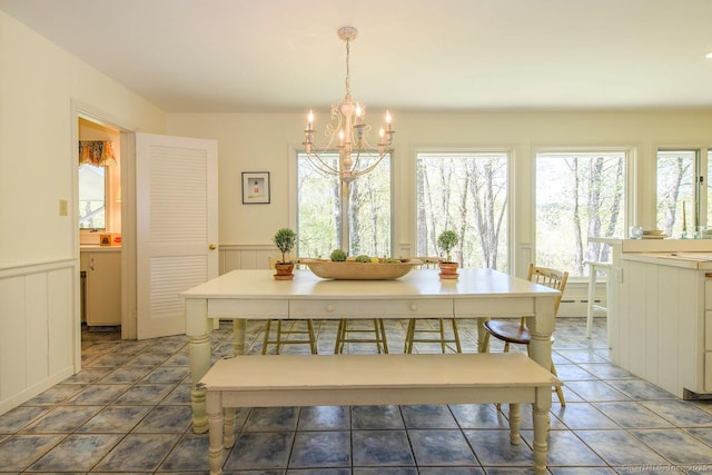 tiled dining area featuring an inviting chandelier, wainscoting, and a decorative wall