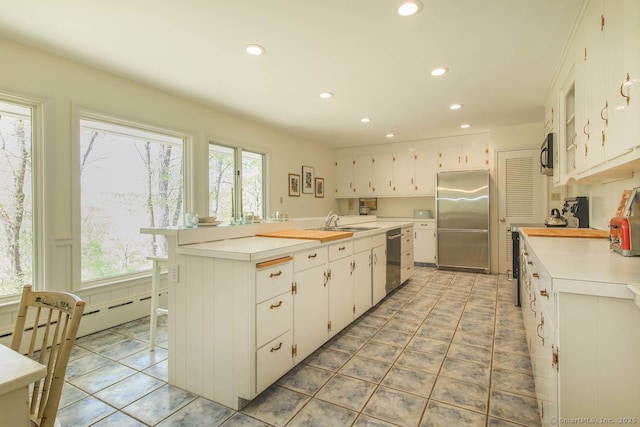 kitchen featuring recessed lighting, a baseboard heating unit, white cabinets, and stainless steel appliances