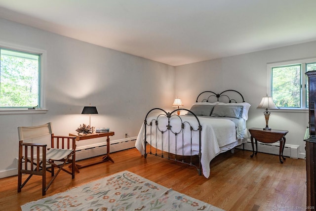bedroom with a baseboard radiator, wood finished floors, baseboard heating, and multiple windows